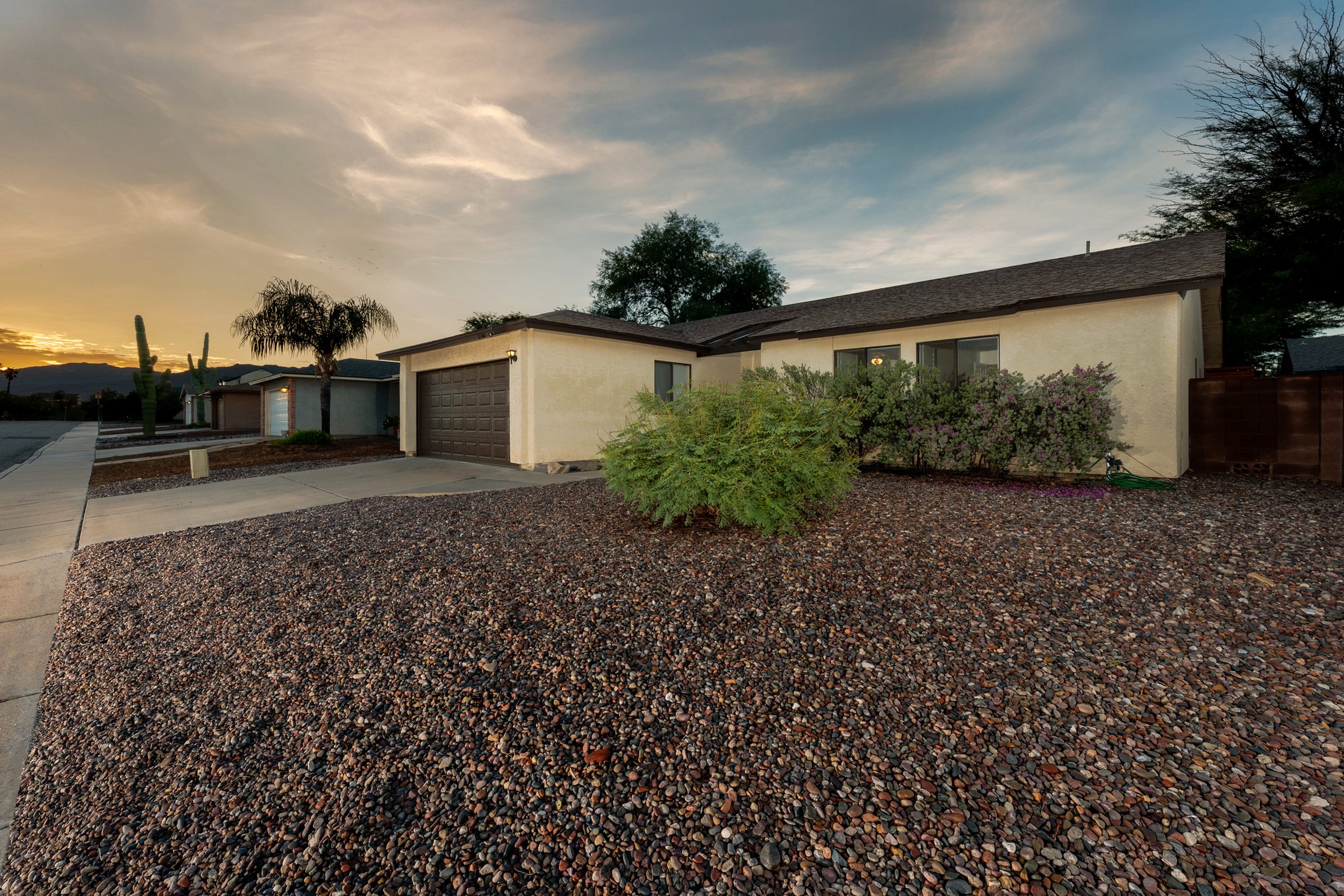 Wide street approach with desert hardscape and mountain line.