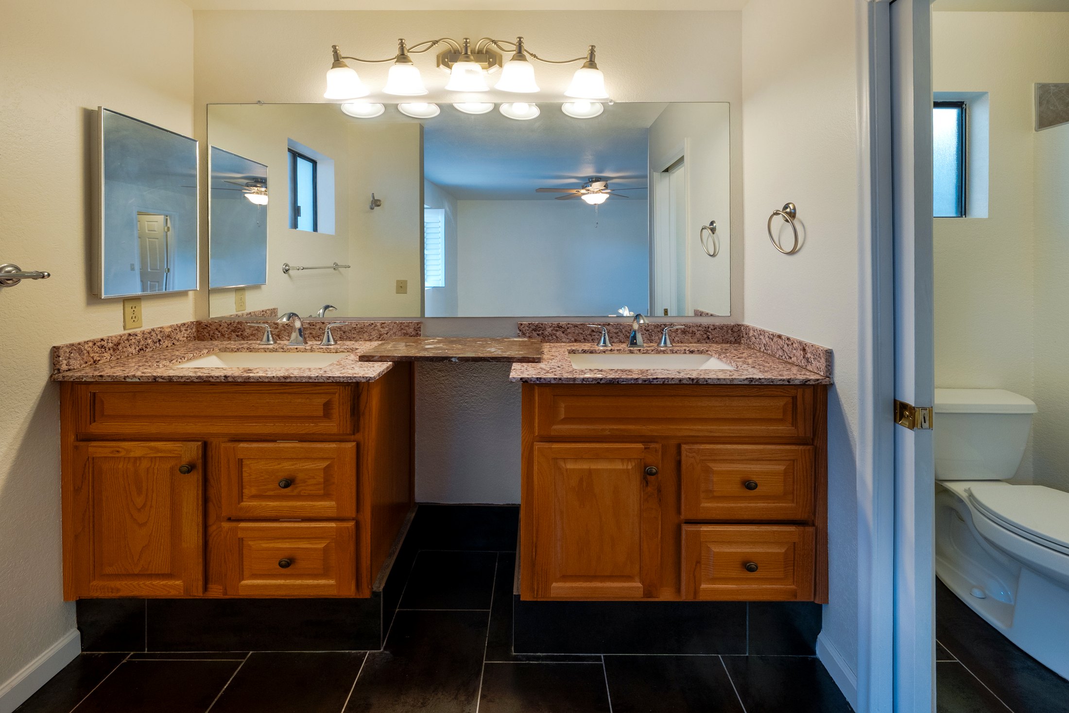 Dual vanity with granite tops and dark tile.