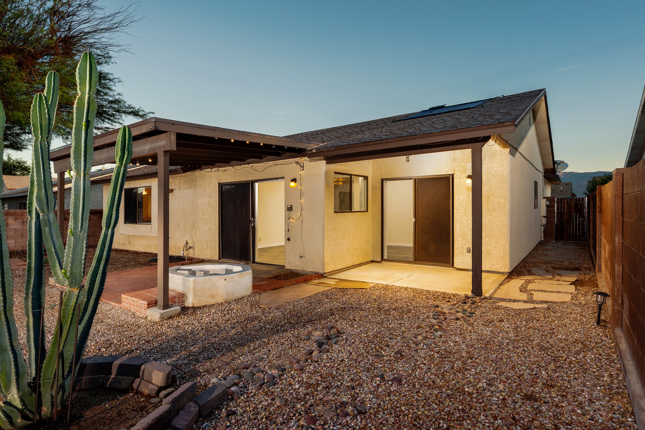 Twilight rear elevation with patio cover and yard lights.