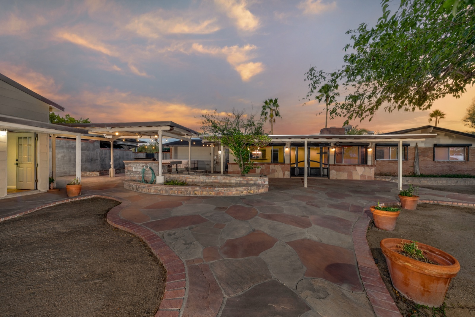 Backyard at sunset with a covered patio and curved stone paving