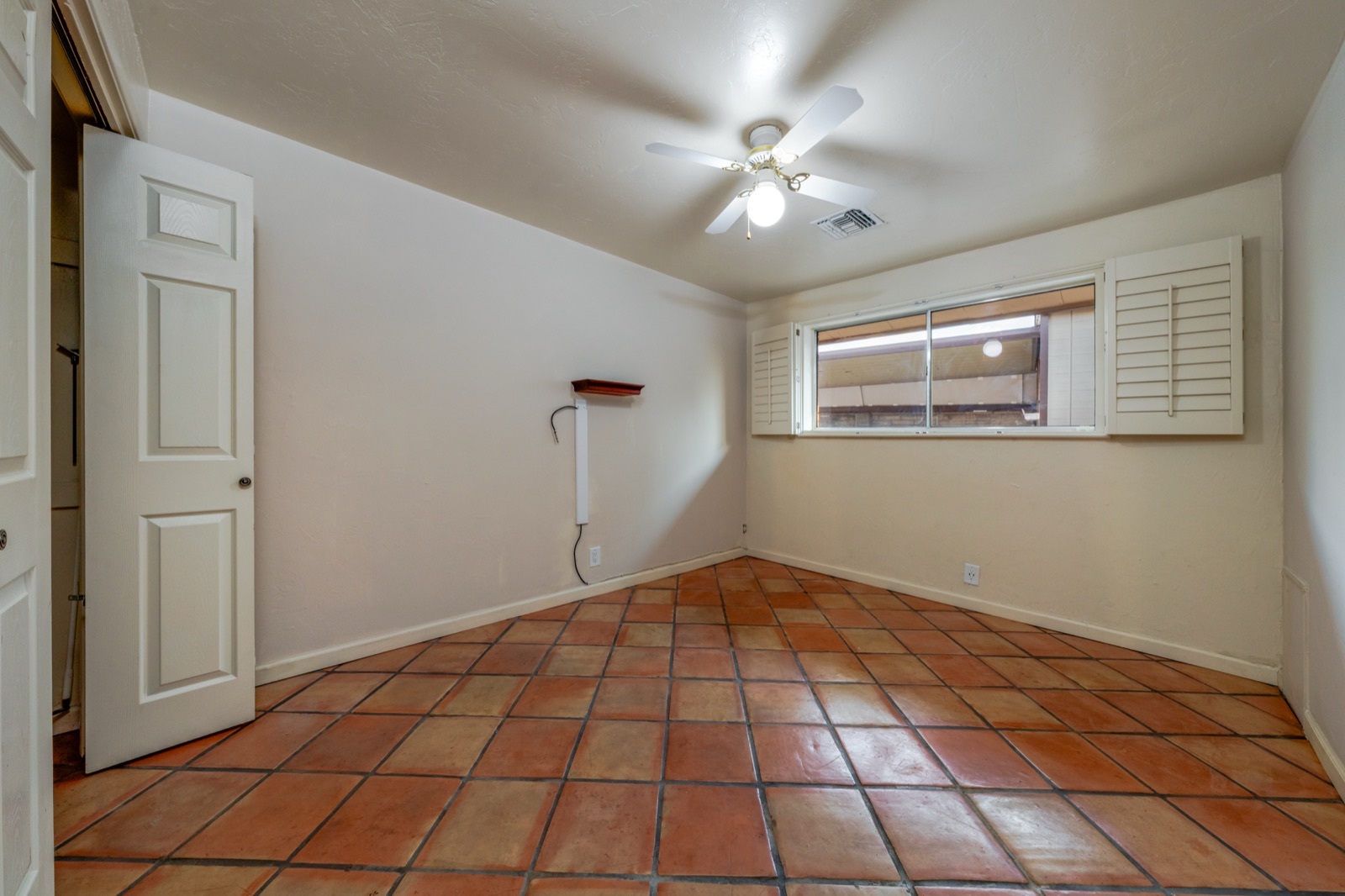 Second bedroom with tile floors and a shuttered window