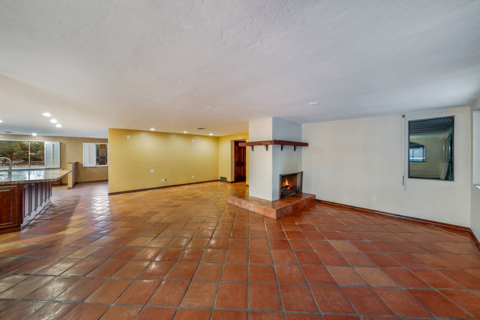 Unfurnished living area with terracotta-colored tile and a central fireplace feature