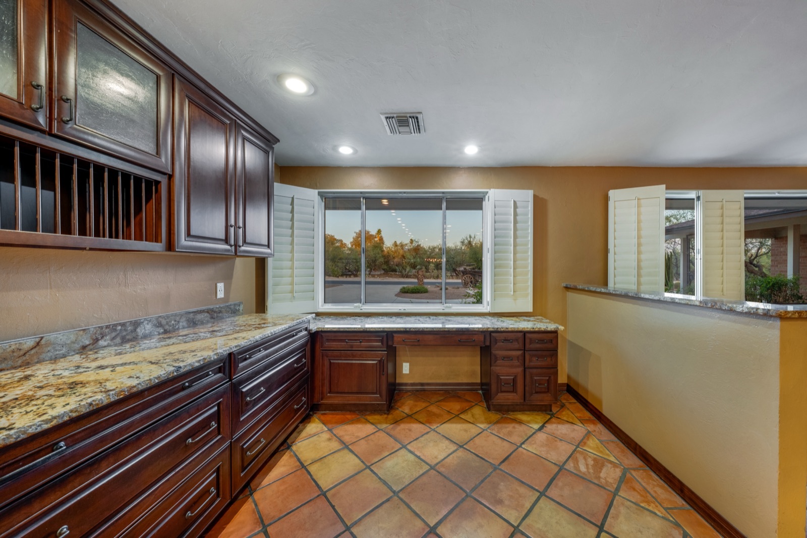 Wood kitchen cabinets, bottle storage and a built-in desk below a window