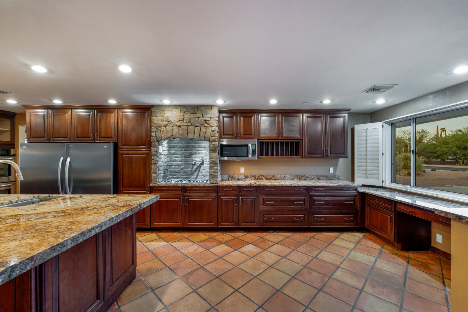 Kitchen cooking area with a pot filler, stone surround and wood cabinetry