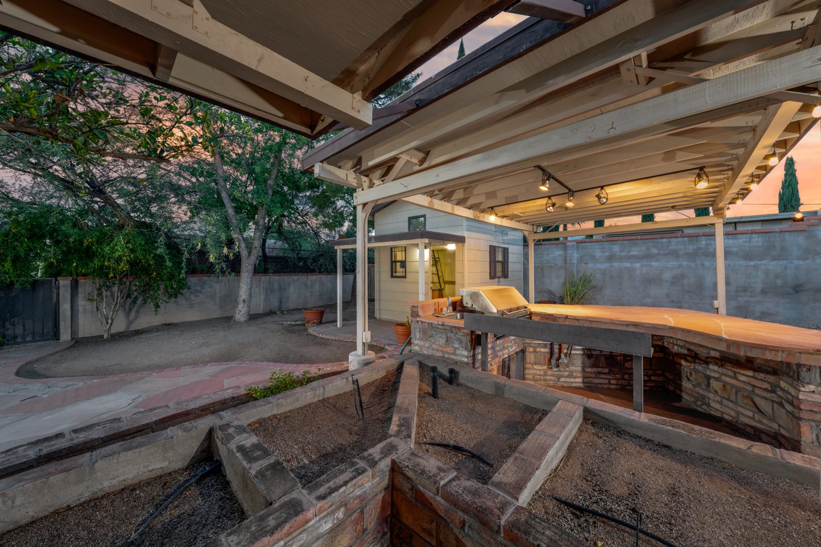Covered outdoor kitchen with a built-in grill, counter seating and a stone counter