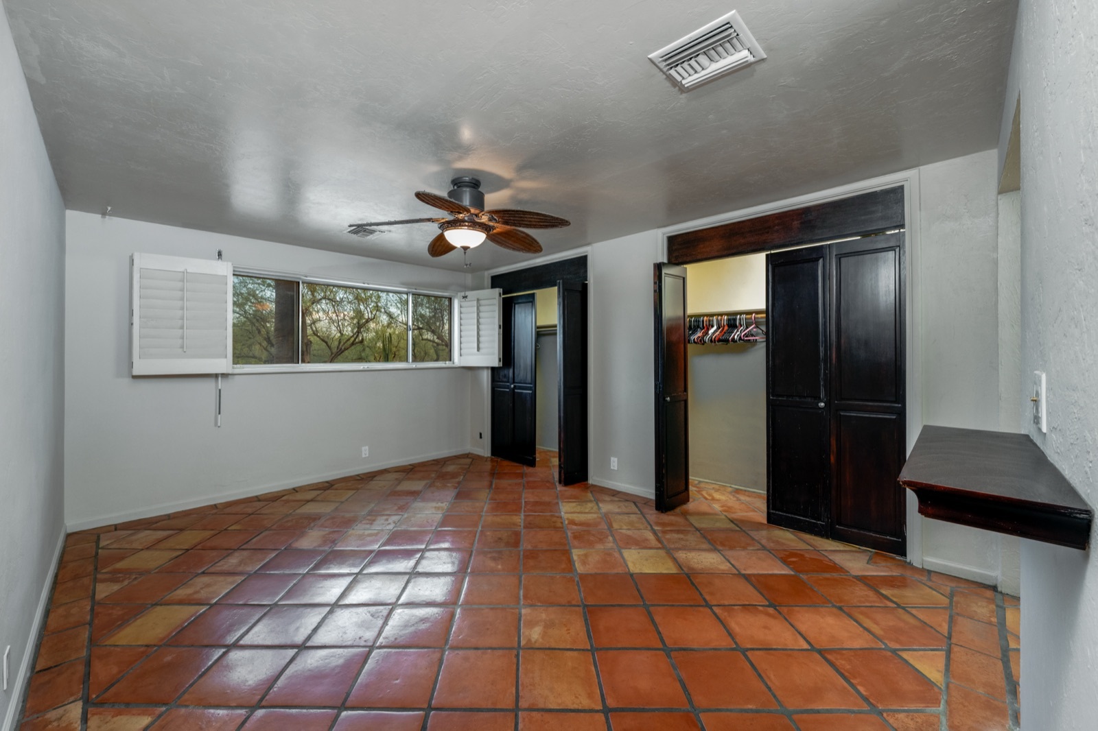 Unfurnished primary bedroom with tile floors, shutters and a corner fireplace feature