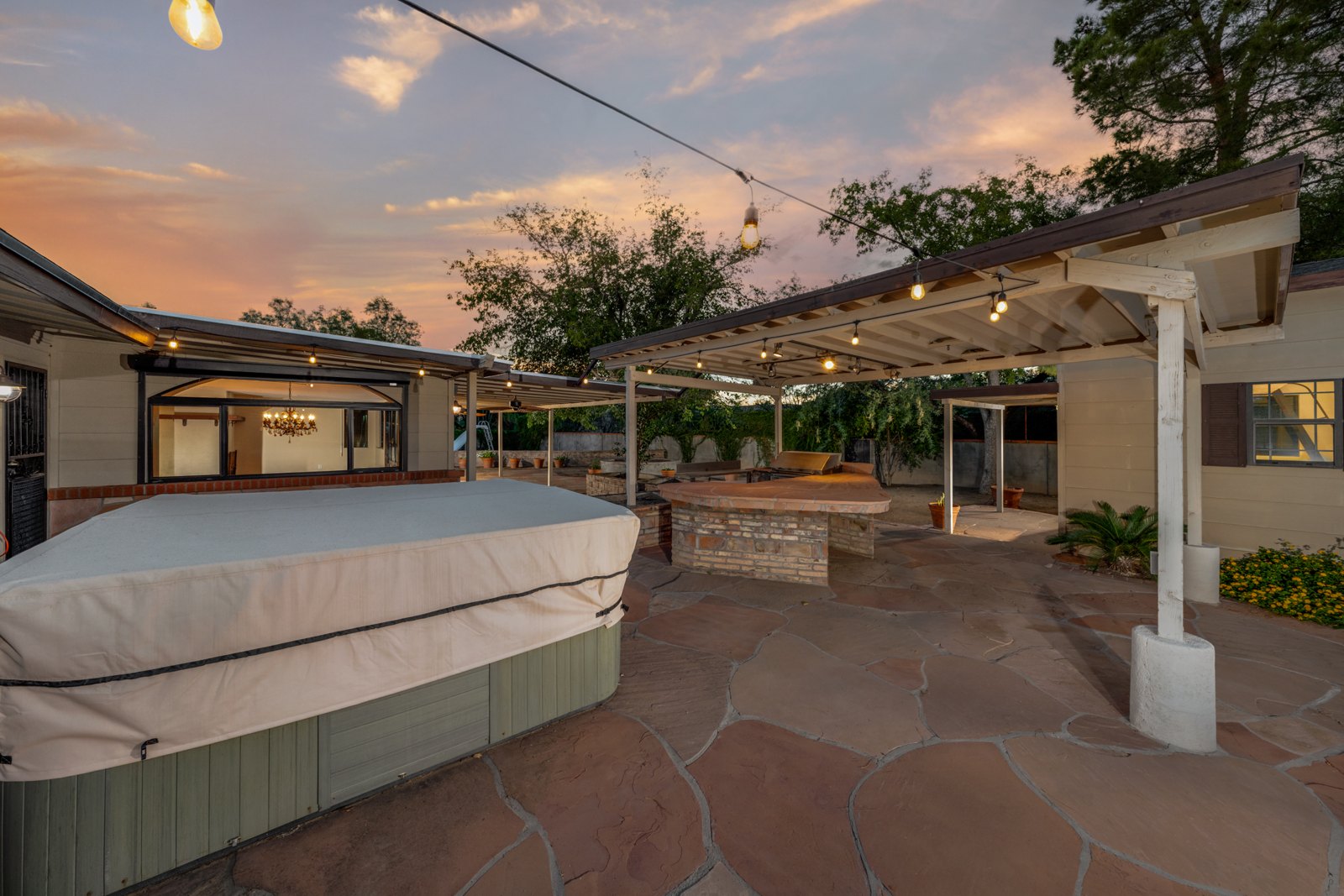 Covered hot tub beside the paved backyard and outdoor kitchen